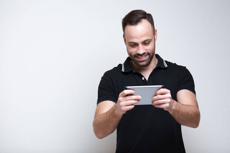 微笑的年轻人在白色背景的智能手机上玩电子游戏