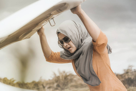亚洲穆斯林女士的肖像，她的汽车引擎在偏远城市的道路上有问题