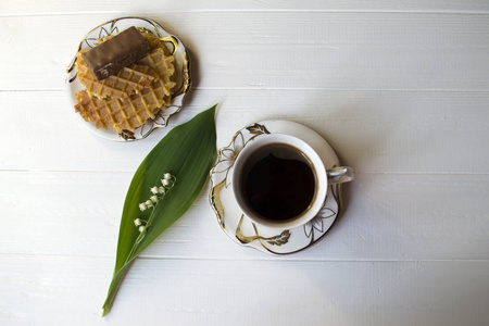 山谷的莉莉，一杯咖啡和甜点放在白色的木桌上。