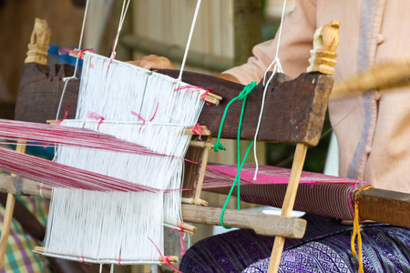 泰国的老妇女正在使用家用织布机织布，用于自制丝绸或纺织品生产