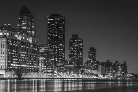 曼哈顿天际线和东河在夜间从罗斯福岛纽约看到。