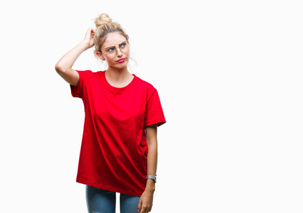 年轻漂亮的金发女人穿着红色的T恤和眼镜，在孤立的背景下困惑和好奇的问题。 不确定，带着怀疑的想法，手在头上。 沉思的概念。
