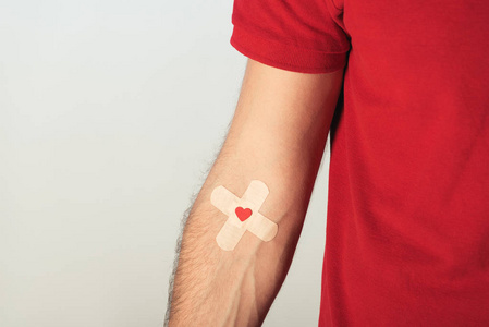 红色T恤患者的部分视图，灰色背景下的石膏献血概念