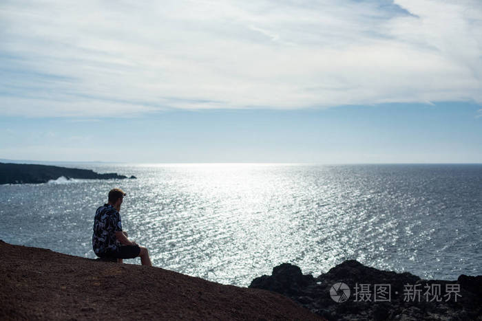 一个人坐在石头上看着大海. 著名的埃尔戈沃·兰扎罗特海滩.