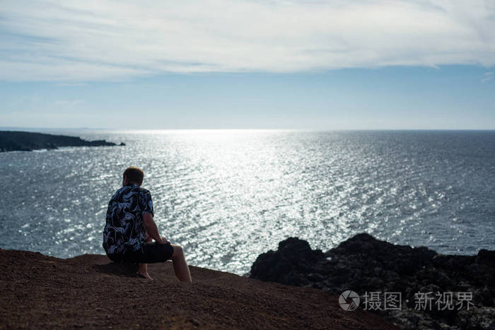 一个人坐在石头上看着大海著名的埃尔戈沃兰扎罗特海滩