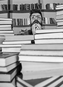 人在紧张的面孔之间在图书馆堆书, 背景书架。老师或学生胡子戴眼镜, 坐在桌子上看书, 弥散。科学发现概念