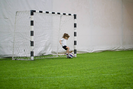 在室内踢足球。一个小女孩成功地保护了足球大门