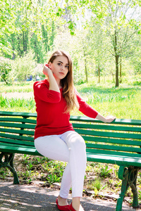 一个女孩的肖像。 穿着红色夹克。 坐在长凳上。