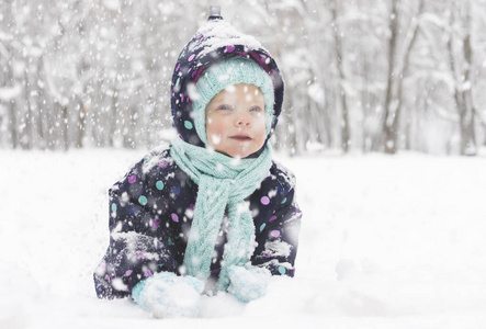 穿冬季连衣裙的婴儿在第一场雪中感到高兴