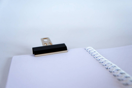 黑色金属夹钳剪裁小白色笔记本，并隔离在白色背景上。