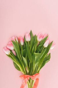 春天花束的顶部视图，郁金香和丝带隔离在粉红色上