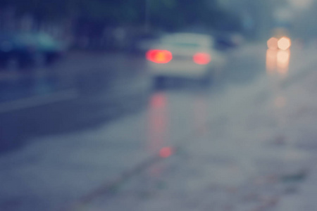 夜间在城市里行驶的车辆在雨中模糊了背景