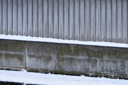 冬季雪覆盖路面旁边的混凝土墙