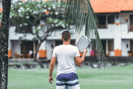 年轻的自由职业者与笔记本电脑在巴厘岛的绿色热带公园