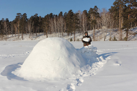 穿暖和衣服的人在冬天的西伯利亚俄罗斯雪坡上搭建一个冰屋