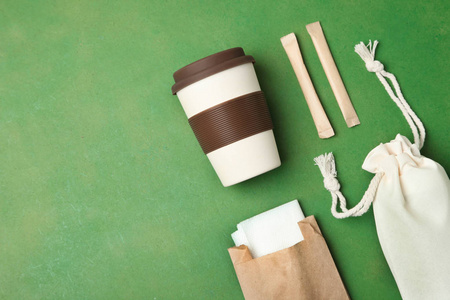 环保袋，可重复使用的竹杯和工艺包装在绿色背景。 概念生态保护。 平躺复制空间。 环保材料。