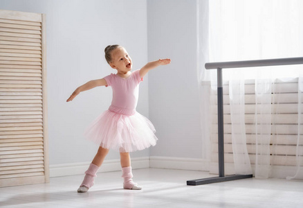 可爱的小女孩梦想成为芭蕾舞演员。 穿着粉红色芭蕾舞裙在房间里跳舞的女孩子。 女婴正在学习芭蕾。