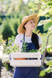 园艺概念。美丽的年轻妇女园丁与花在木箱