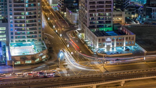 大城市夜间时间推移道路交叉口的鸟瞰图。 阿联酋迪拜码头区的城市景观，配有汽车和电车