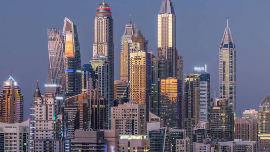 迪拜码头塔全景白天到晚上过渡时间灯打开。 阿联酋摩天大楼的夜间照明。 来自JLT的鸟瞰图