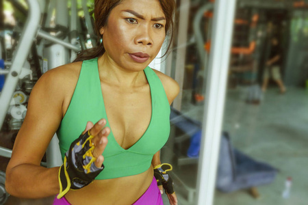年轻有魅力和运动的亚洲印尼运动女性在健身房健身俱乐部跑步机上跑步，训练艰苦的慢跑锻炼，专注于健康的生活方式和牺牲