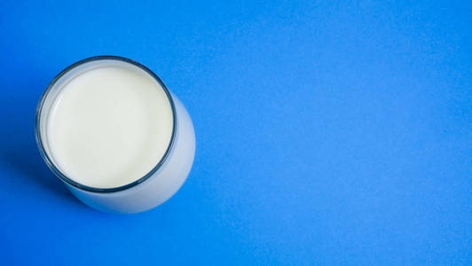 蓝色背景上的透明牛奶玻璃。上面的风景。