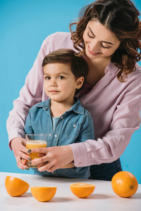 快乐的妈妈给一个可爱的小儿子一杯新鲜的橙汁