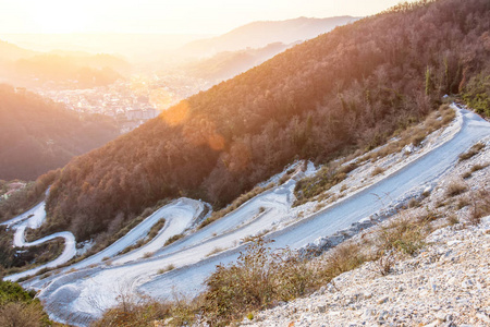 蜿蜒曲折的蛇形道路在岩石山脉之间升起。 日落时分