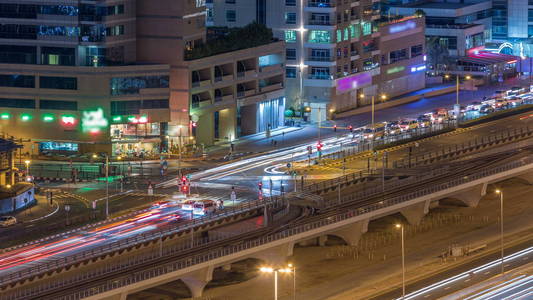 大城市夜间时间推移道路交叉口的鸟瞰图。 阿联酋迪拜码头区的城市景观，配有汽车和电车