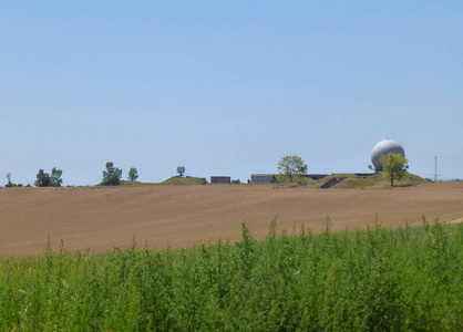 一个军事雷达站在一座被田野包围的小山上的照片
