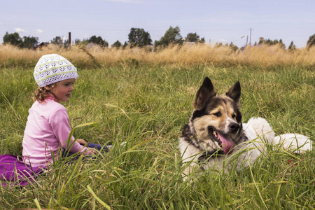 小女孩和一只白狗坐在草地上