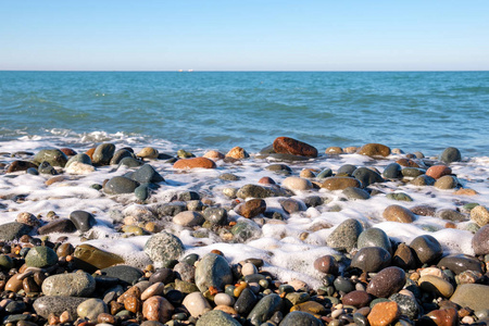 海滩上五颜六色的潮湿岩石被泡沫般的波浪覆盖着
