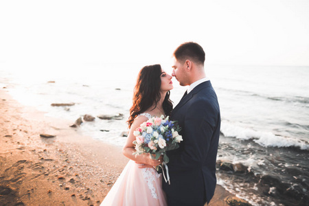 幸福和浪漫的场景，只是结婚的年轻婚礼夫妇在美丽的海滩上摆姿势的