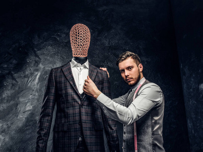 一位时装设计师在一个黑暗的裁缝工作室里检查定制的优雅男装的质量
