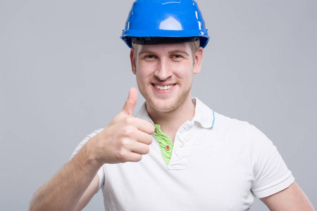年轻的微笑工人戴着蓝色的安全帽