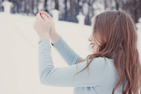 快乐和微笑的女孩在下雪时保持街道上的孟加拉灯。 冬季概念。 新年概念。