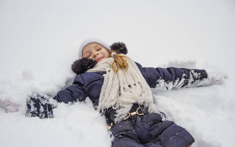 冬天公园里躺在雪地里的快乐女孩