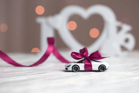 玩具车的背景上有一个蝴蝶结的爱这个词。 礼品带玩具车