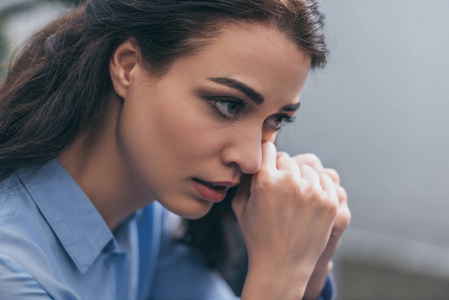 房间里穿蓝色衬衫的悲伤哭泣的女人的肖像悲伤混乱的概念