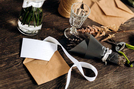 木桌上有一束鲜花酒杯明信片信封和白色丝带