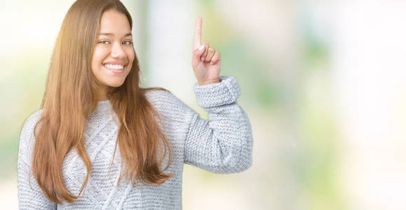 年轻漂亮的黑发女人穿着毛衣，在孤立的背景上指点着成功的想法。 退出并快乐。 一号。