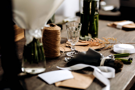 木桌上有酒杯小花束明信片信封线和白丝带