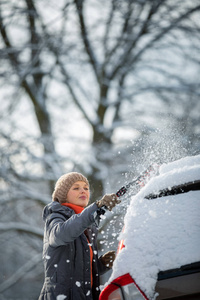 大雪后，一位漂亮的年轻女士在雪地上清洁她的汽车彩色色调图像