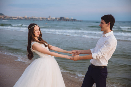 幸福的新婚夫妇在海洋海滩上互相牵着彼此的手。美丽的新娘和新郎新娘在户外婚礼