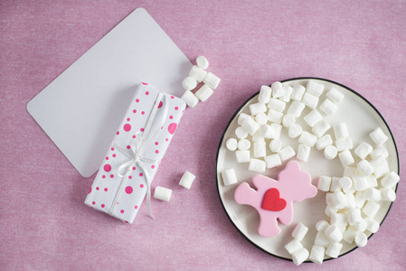 用丝带系的礼品盒位于粉红色背景盒上，粉红色熊玩具棉花糖，上面有白色卡片，用于添加文本水平
