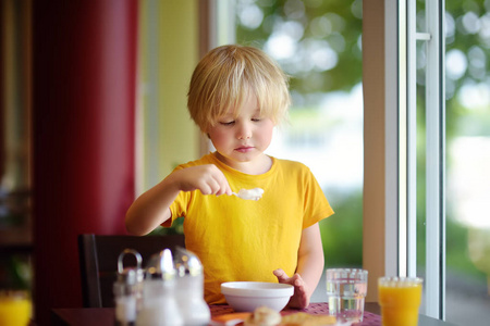 小男孩在旅馆餐馆吃健康的早餐。在家吃大餐。儿童健康食品。