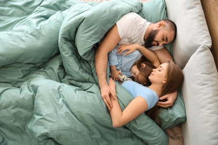 幸福的一家人睡在家里的床上