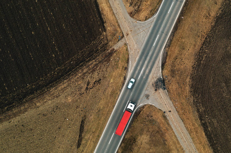 汽车和卡车在笔直的道路上，通过平原乡村景观，从无人驾驶的POV空中俯瞰