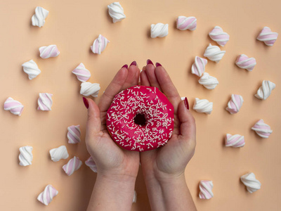 s hand holding donut with marshmallow on peach background