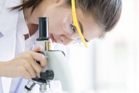 亚洲青年学生科学家在实验室用显微镜研究。
